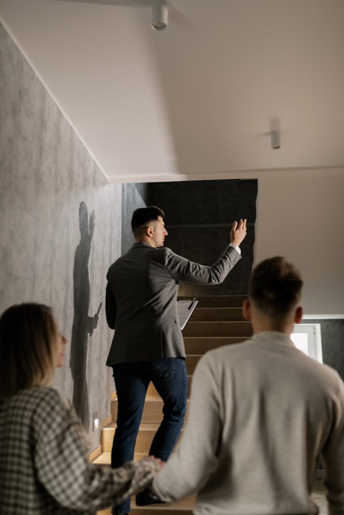 A real estate agent leads a couple on a house tour, highlighting interior features in a modern home.